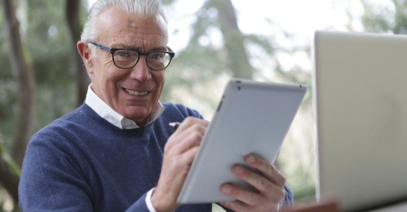 Old Gadgets - Man in Blue Sweater Holding White Tablet Computer